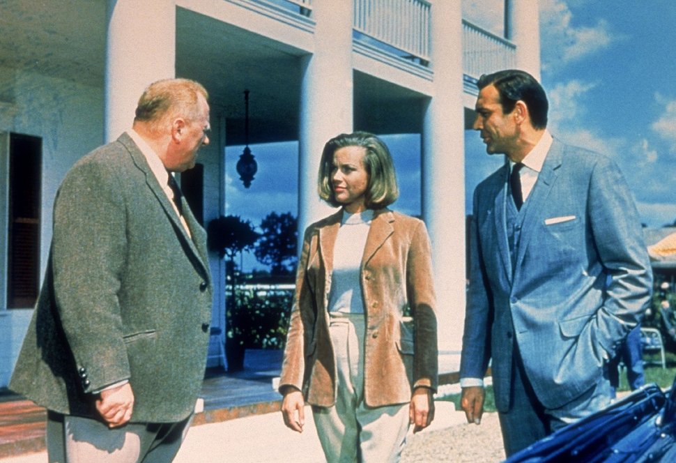 Goldfinger (Gert Fröbe, l.) ist es mit Hilfe der Pilotin Pussy (Honor Blackman) gelungen, James Bond (Sean Connery) gefangen zu nehmen. – Bild: TVNOW / © 1964 Danjaq