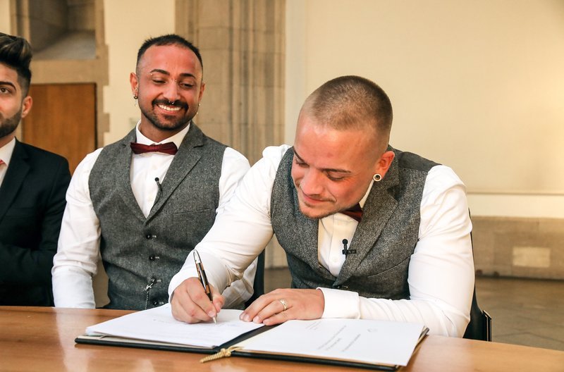 Ibrahim (l) und Benjamin auf dem Standesamt, Benjamin unterschreibt die Heiratsurkunde. – Bild: WDR/​CoellnColoer/​Fischer/​Nischk