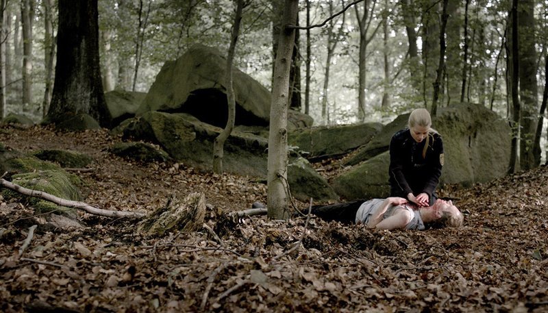 Polizistin Elke (Henrike von Kuick) mit dem tödlich verletzten Tschechen im Wald. – Bild: MDR/​Filmuniversität Babelsberg