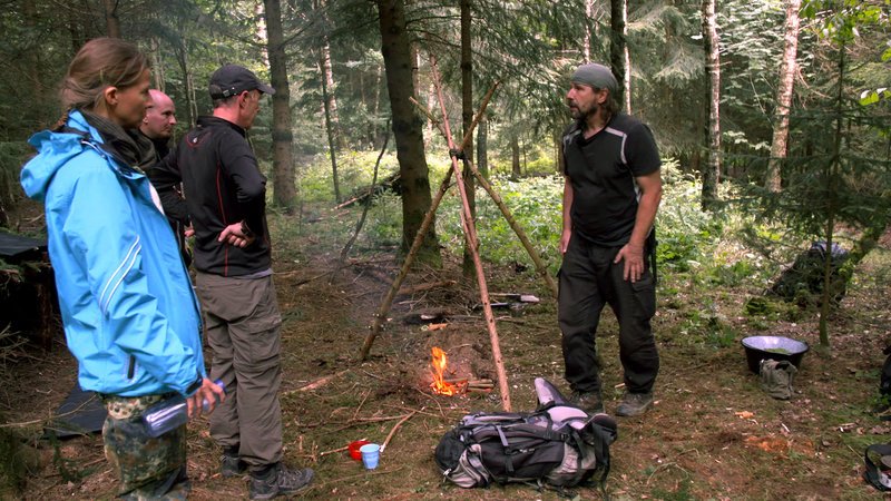 Survival-Trainer Armin Hock zeigt den Teilnehmern, wie man sich alleine im Wald ernähren kann. – Bild: ZDF und Kelvinfilm GmbH/​Tiemo Fenner