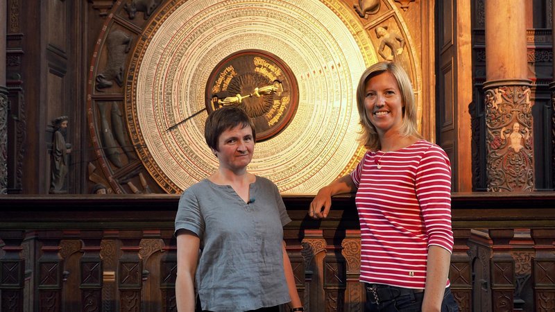 Susanne Gebhardt (re.) mit Heike Tröger vor der Astronomischen Uhr der Marienkirche Rostock. – Bild: ZDF und SWR/​Ildico Wille.