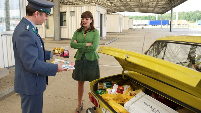 Elkes (Katharina Wackernagel) Mitbringsel aus dem Westen werden von einem Zollbeamten inspiziert. – Bild: MDR / © MDR/Marc Meyerbroeker Elkes (Katharina Wackernagel) Mitbringsel aus dem Westen werden von einem Zollbeamten inspiziert. – Bild: MDR / © MDR/Marc Meyerbroeker