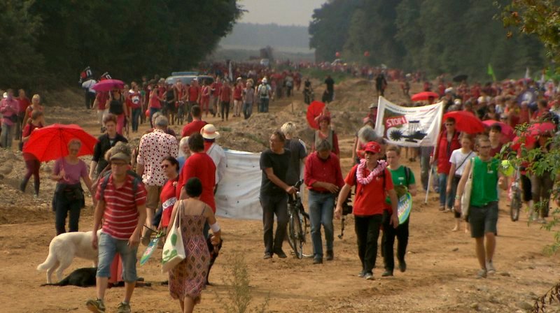 Im August 2017 bildeten 3.000 Menschen eine rote Linie entlang der alten A4 und stellten sich damit schützend vor dem Hambacher Forst. – Bild: WDR Im August 2017 bildeten 3.000 Menschen eine rote Linie entlang der alten A4 und stellten sich damit schützend vor dem Hambacher Forst. – Bild: WDR