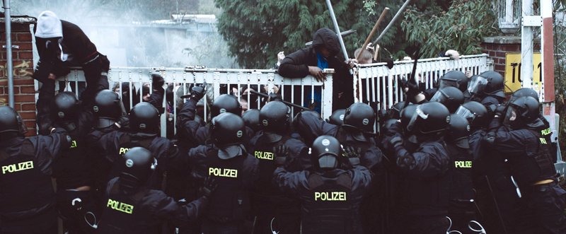 Nachdem einer der Flüchtlinge getötet wurde, versuchen andere aus der Transitzone auszubrechen, gehindert von einem massiven Polizeieinsatz. – Bild: SWR/augenschein Filmproduktion Nachdem einer der Flüchtlinge getötet wurde, versuchen andere aus der Transitzone auszubrechen, gehindert von einem massiven Polizeieinsatz. – Bild: SWR/augenschein Filmproduktion