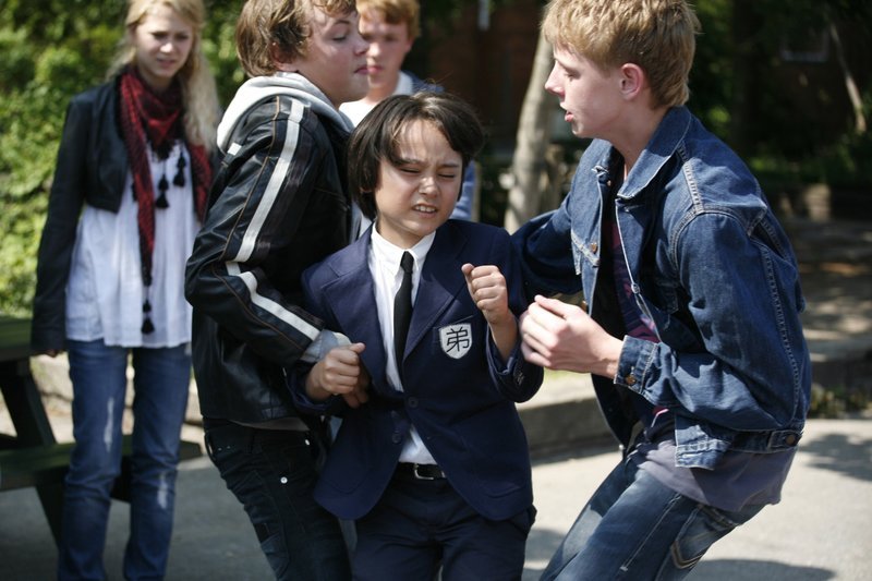 Shin (Miki Andersen) wird von älteren Schülern angegriffen. Doch er weiß sich auf seine Art zu wehren. – Bild: KI.KA/​Ilse Schoutteten