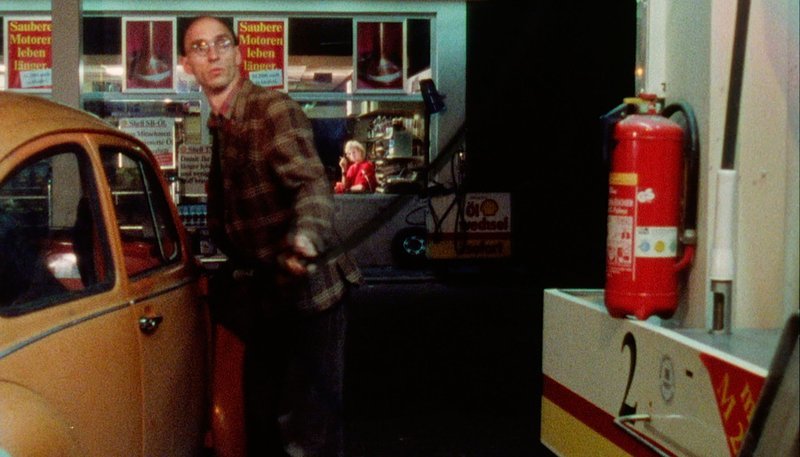 Er, der Kunde (Bernd Raucamp) tankt täglich für 10 Mark, weil er sich für die Tankstellenkassiererin (Nadja Engelbrecht) interessiert. – Bild: rbb/​Deutsche Kinemathek