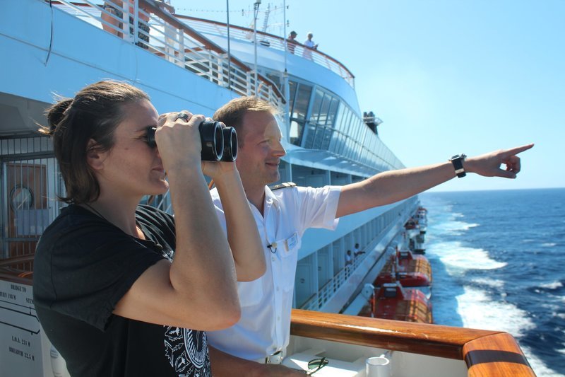 Offizier Christian Baumann zeigt Nadine Angerer den Maschinentelegraphen und den Toter-Mann-Knopf auf der Brücke. Plötzlich entdeckt der Rudergänger backbords eine Gruppe Wale, die dicht neben dem Schiff auftauchen. Nadine beobachtet die Wale mit dem Fernglas. – Bild: Bewegte Zeiten Filmproduktion GmbH/​BR/​Gerrit Mannes