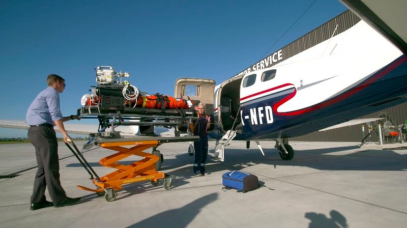 Das Ausladen der Patienten erfordert noch einmal Fingerspitzengefühl nach dem aufregenden Flug. Weitere Fotos auf Anfrage. – Bild: phoenix/​NDR/​Sandra Ratzow