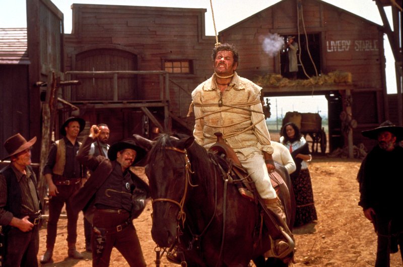 Höhepunkt ihres Cowboy-Spektakels: Tuco (Eli Wallach, M.) hat die Schlinge um den Hals, und Freund Joe (Clint Eastwood, rechts oben) zerschießt mit seinem Gewehr den Strick. – Bild: ZDF und Angelo Novi