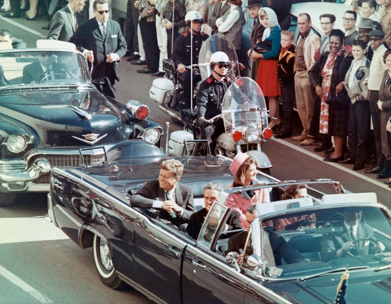 Dallas, 22. November 1963: Präsident John F. Kennedy und Gattin Jackie Kennedy lächeln den vielen freundlich winkenden Menschen am Straßenrand zu. Nur wenige Minuten später, als die Autokolonne die Dealey Plaza erreicht, fallen die tödlichen Schüsse. – Bild: ARTE France /​ © Bettmann/​Corbis