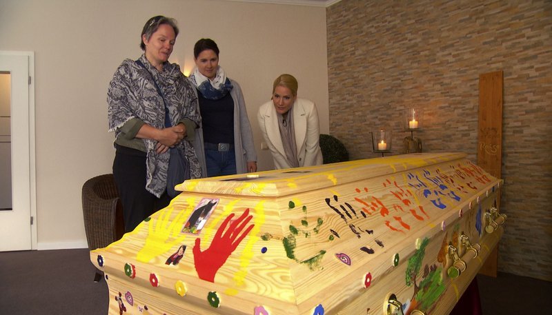 v.l.: Mutter Ute, die Ehrenamtliche Nicole Daffinger und Judith Rakers beim Sarg von Tochter Katharina. – Bild: NDR