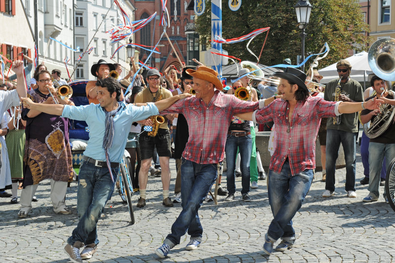 Sirtaki tanzende Cowboys in München: Nektarios (Adam Bousdoukos, r.) mit Ehemann Lambert (Heiner Lauterbach, m). – Bild: ZDF und Kerstin Stelter Sirtaki tanzende Cowboys in München: Nektarios (Adam Bousdoukos, r.) mit Ehemann Lambert (Heiner Lauterbach, m). – Bild: ZDF und Kerstin Stelter