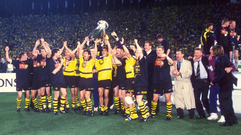 Es war die Woche, in der der Pott bebte! Im Mai 1997, vor genau 20 Jahren, räumten zwei Ruhrgebiets-Vereine innerhalb einer Woche die wichtigsten Trophäen des europäischen Fußballs ab. Und ganz Deutschland fieberte mit dem Revier. Der FC Schalke 04 gewann in Mailand nach einem nervenzerreißenden Spiel den UEFA-Pokal – im Elfmeterschießen. Sieben Tage später besiegte Borussia Dortmund das hochgewettete Juventus Turin und wurde Champions-League-Sieger – und das ausgerechnet in München! Beide Clubs traten als Außenseiter gegen Spitzenvereine Italiens an – und sorgten für Sensationen.- Dortmunds Spieler und Ottmar Hitzfeld mit dem Champions-League-Pokal, 1997. – Bild: WDR/​imago