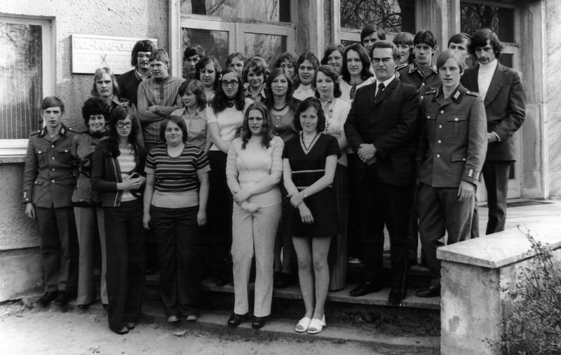 Klassentreffen in Golzow, 26. April 1975. Viele der Jungen sind jetzt Soldaten. Nie wieder kamen so viele auf ein gemeinsames Bild. 1. Reihe, von links: N.N., die erste Lehrerin Marlies Teike, etc.; 2. Reihe: N.N., Eckhard, Dieter, (hinter ihm links: Eckhard, hinter ihm rechts: Winfried), N.N., N.N., Marieluise (hinter ihr links: Brigitte), Elke, N.N. (dahinter verdeckt: Gudrun) und Bernd (hinter ihm rechts: Willy) . – Bild: BR/​Progress Film-Verleih/​DEFA