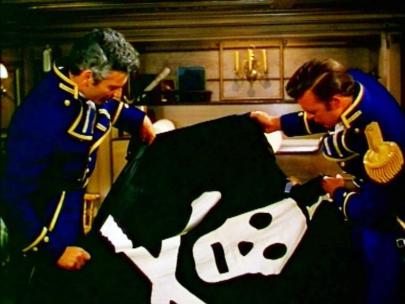 Der Commodore der US-Marine Kapitän David Porter (Jeff Chandler, l.) und sein erster Offizier Lt. David Farragut (Scott Brady) begutachten die Piratenflagge, die Teil ihres Geheimauftrages ist. – Bild: RTL NITRO