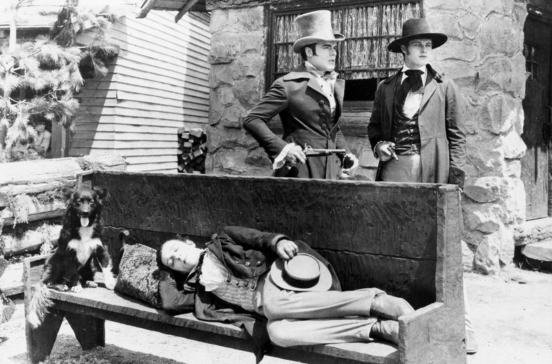 William McKay (Buster Keaton) schläft gemütlich auf der Bank, während Canfields ältester Sohn (Francis X. Bushman Jr., li.) und Lee Canfield (Craig Ward, re.) nach ihm suchen. – Bild: Lobster Films
