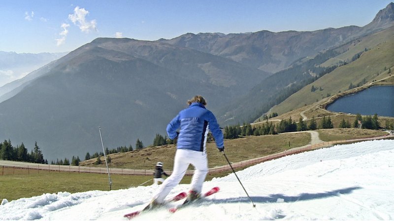 Skifahren im Grünen: Mitte Oktober eröffnet Kitzbühel seine ersten Pisten. Skifahren auf Kunstschnee bei 20 Grad zur Saisoneröffnung. – Bild: BR/​SWR
