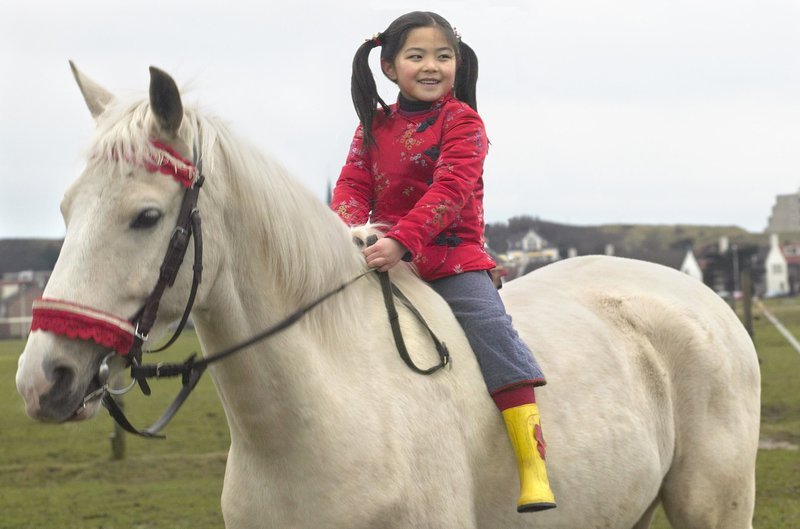 Winky (Ebbie Tam) will ein Pferd zum Liebhaben – und sie will es behalten dürfen! Der Schimmel, auf dem sie reitet, gehört aber doch dem Nikolaus. – Bild: BR/​Victor Arnolds