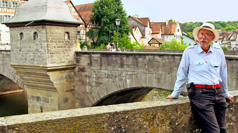  Der Künstler Bernhard Deutsch bringt mit seinem besonderen Charme den Schwäbisch-Haller Besuchern die Henkersbrücke nahe. – Bild: SWR /​ SWR-Presse/​Bildkommunikation