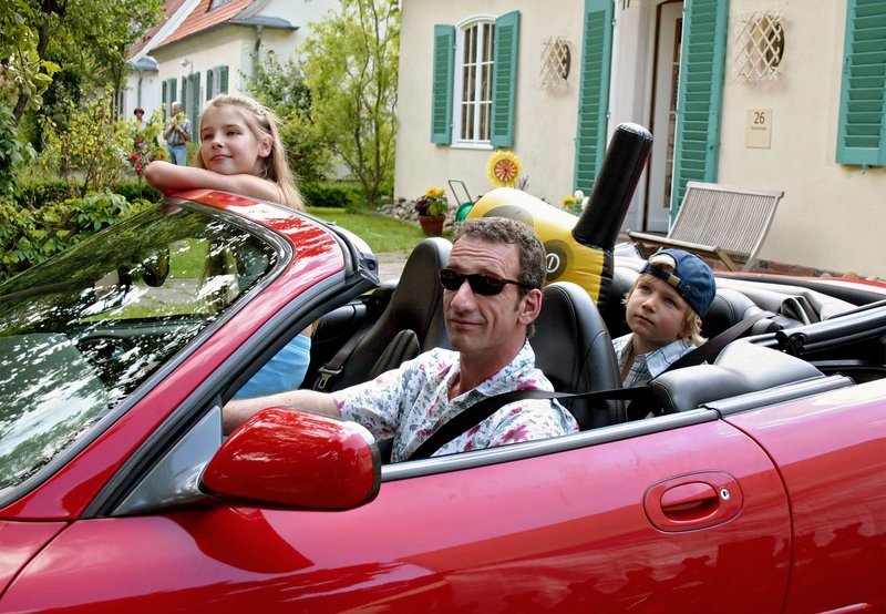 Der allein erziehende Vater Dr. Peter Grainernapp (Heio von Stetten) macht mit seinen beiden Kindern Jennifer (Gina Sehlmeyer) und Philipp (Alexander Seidel) einen Badeausflug im neuen Luxusauto. – Bild: MDR/Degeto/Sandor Domonkos Der allein erziehende Vater Dr. Peter Grainernapp (Heio von Stetten) macht mit seinen beiden Kindern Jennifer (Gina Sehlmeyer) und Philipp (Alexander Seidel) einen Badeausflug im neuen Luxusauto. – Bild: MDR/Degeto/Sandor Domonkos