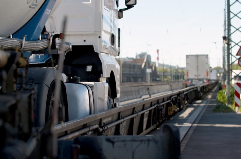 In Freiburg im Breisgau geht es für die Lastkraftwagen auf die Schiene. Anhänger samt Zugmaschine werden via Eisenbahn durch die Schweiz bis nach Italien transportiert. – Bild: ARD alpha In Freiburg im Breisgau geht es für die Lastkraftwagen auf die Schiene. Anhänger samt Zugmaschine werden via Eisenbahn durch die Schweiz bis nach Italien transportiert. – Bild: ARD alpha