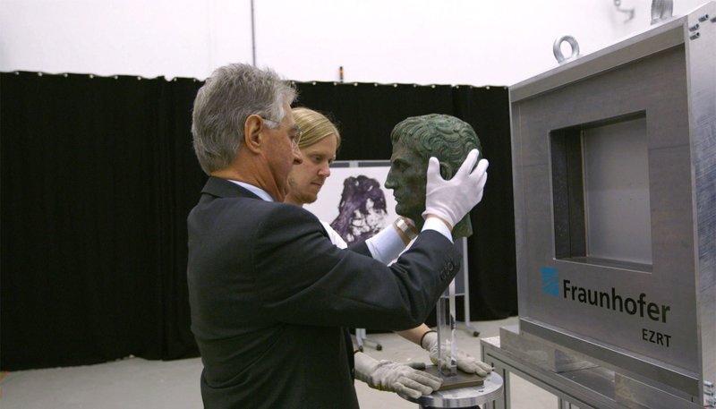 Als einem Schweizer Milliardär Zweifel kommen, dass seine bei Sotheby’s erstandene Bronzebüste ein Original ist, wendet er sich an den Hallenser Archäologen Stefan Lehmann. Dieser ist Experte für die Enttarnung von Fälschungen. Der Film verfolgt die Beweisführung bis zur Gerichtsverhandlung in Berlin im Herbst 2015. – Der Kunstgutachter Harald Müller (re.) prüft den Bronze-Augustus im Fraunhofer Institut. – Bild: rbb/​Anne Misselwitz