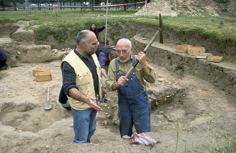 Peter (Peter Lustig, r.) packt an. Auf einer Ausgrabungsstätte schwingt er die Hacke, wird aber von einem der Experten (Ludger Burmann, l.) gestoppt. Peter erfährt von ihm mehr über alte Scherben und das Leben der Römer. – Bild: ZDF und Christiane Pausch