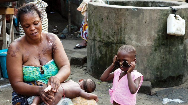 Yolande im Innenhof mit ihren Kindern im Benin. – Bild: WDR/​Bildersturm Filmproduktion GmbH/​Heike Frielingsdorf
