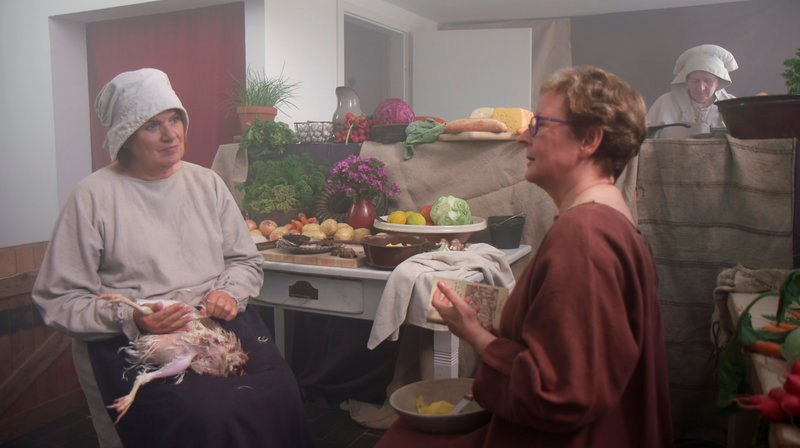 Christine Westermann (l), im Kostüm einer Köchin zur Biedermeierzeit, im Gespräch mit Barbara Becker-Jaklihat, die für ihren Roman „Mord im Biedermeier“ Kölner Kochbücher zu Beginn des 19. Jahrhunderts studiert hat. – Bild: WDR/​Good Karma Productions