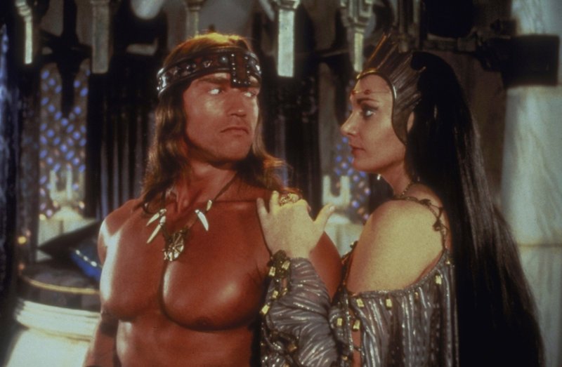 Die schöne Königin Taramis (Sarah Douglas, r.) beauftragt Conan (Arnold Schwarzenegger, l.) mit der Suche nach einem geheimnisvollen Schatz. Als Dank für seine Hilfe verspricht sie ihm, seine tote Gefährtin wieder zum Leben zu erwecken… – Bild: Universal Pictures Lizenzbild frei