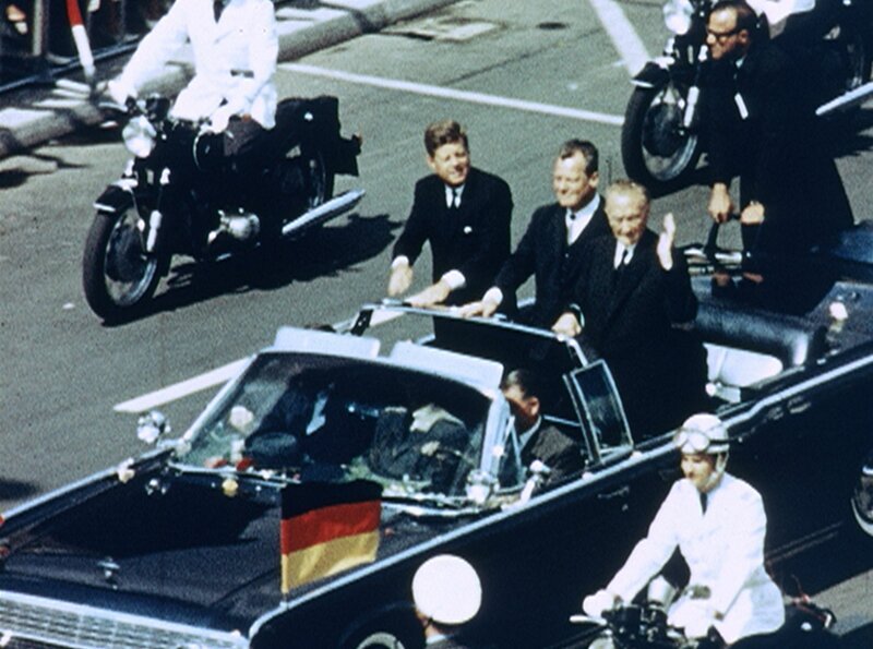 Einsfestival MIT KENNEDY DURCH DEUTSCHLAND, am Mittwoch (01.10.14) um 15:45 Uhr. Vier Tage im Juni 1963: John F. Kennedy besucht Deutschland. Sein erster Besuch als Präsident. Ob in Köln, Bonn, Frankfurt oder Berlin, Kennedy wird frenetisch gefeiert, nie zuvor hat es in Deutschland solche Begeisterung für Amerika gegeben. Und niemals danach. Der Kennedy-Besuch im Juni 1963 markiert bis heute einen Höhepunkt der transatlantischen Partnerschaft zwischen den USA und Deutschland. – Autokorso durch Berlin mit dem amerikanischen Präsidenten John F. Kennedy (li.), Berlins Regierendem Bürgermeister Willy Brandt und Bundeskanzler Dr. Konrad Adenauer (re.) – Bild: rbb Einsfestival MIT KENNEDY DURCH DEUTSCHLAND, am Mittwoch (01.10.14) um 15:45 Uhr. Vier Tage im Juni 1963: John F. Kennedy besucht Deutschland. Sein erster Besuch als Präsident. Ob in Köln, Bonn, Frankfurt oder Berlin, Kennedy wird frenetisch gefeiert, nie zuvor hat es in Deutschland solche Begeisterung für Amerika gegeben. Und niemals danach. Der Kennedy-Besuch im Juni 1963 markiert bis heute einen Höhepunkt der transatlantischen Partnerschaft zwischen den USA und Deutschland. – Autokorso durch Berlin mit dem amerikanischen Präsidenten John F. Kennedy (li.), Berlins Regierendem Bürgermeister Willy Brandt und Bundeskanzler Dr. Konrad Adenauer (re.) – Bild: rbb
