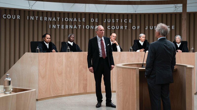 Victor Graf (Ulrich Tukur) steht als Verteidiger der Bundesrepublik Deutschland im Gerichtssaal. – Bild: rbb/​zero one film/​Julia Terjung