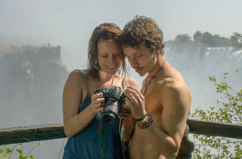 Gabriel (João Pedro Zappa) und Cristina (Caroline Abras) machen Fotos vor den Victoriafällen. – Bild: Damned Films / © Damned Films Gabriel (João Pedro Zappa) und Cristina (Caroline Abras) machen Fotos vor den Victoriafällen. – Bild: Damned Films / © Damned Films