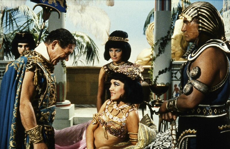 2. Während Cleopatra (Amanda Barrie, Mitte) sich von Mark Anton (Sidney James, l.) die Ausbreitung ihres Reiches verspricht, hott dieser auf ein Schäferstündchen ohne ihren stummen Leibwächter Sosages (Tom Clegg, r.). – Bild: Peter Rogers