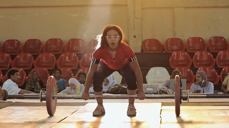 Der letzte Zuruf ihres Trainers Captain Ramadan, bevor Zebiba das Gewicht stemmt, lautet immer: „Steh mit beiden Beinen fest auf dem Boden und stemme das Gewicht mit Ruhe.“ – Bild: ZDF und Mayye Zayed.