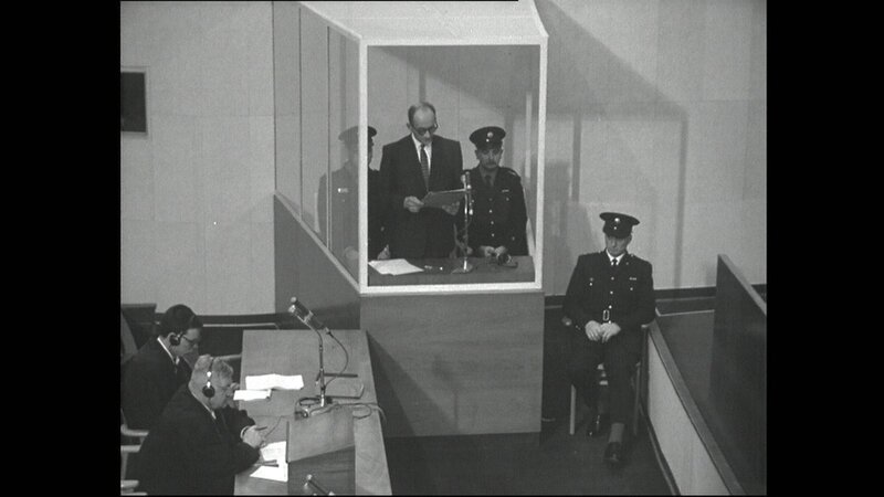 Adolf Eichmann im Glaskasten mit drei Polizisten, Verteidiger Dr. Robert Servatius und sein Assistent (links). – Bild: BR /​ BR