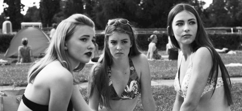 Die drei Freundinnen (von links) Kiara (Marie Löschhorn), Linda (Hannah Kraft) und Heli (Paulina Ferrari) unterhalten sich über Jungs und beobachten die Jungsgruppe um Sami (Daniel Toos). – Bild: SWR/Filmakademie BW Die drei Freundinnen (von links) Kiara (Marie Löschhorn), Linda (Hannah Kraft) und Heli (Paulina Ferrari) unterhalten sich über Jungs und beobachten die Jungsgruppe um Sami (Daniel Toos). – Bild: SWR/Filmakademie BW