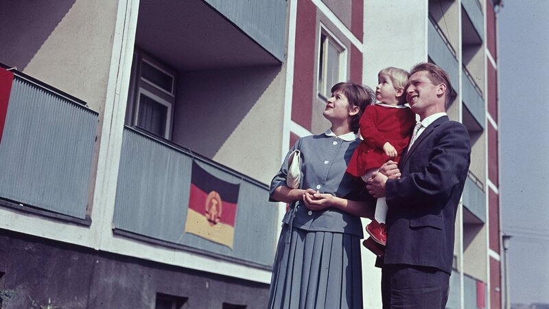 Eine junge Familie vor einem neu fertiggestellten Plattenbau in Ostberlin, 1963. – Bild: ZDF und Wilfried Glienke.