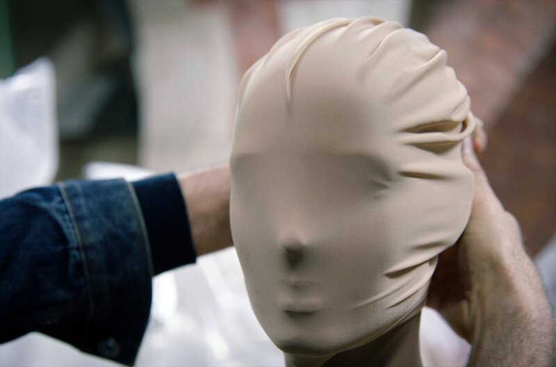 Martin Margiela legt eine Maske an einem Modell an. Der 1957 geborene belgische Modedesigner inspiriert bis heute viele seiner jüngeren Kolleginnen und Kollegen, ohne sein Gesicht in der Öffentlichkeit gezeigt zu haben. – Bild: Reiner Holzemer Film /​ © Reiner Holzemer Film