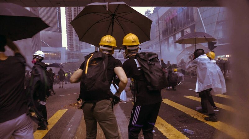 Demonstranten nutzen ihre Regenschirme als Deckung und Abwehr. – Bild: WDR/​Enemy Productions
