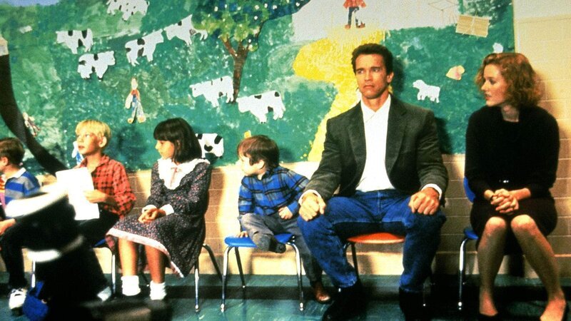 Der Polizist Kimble (Arnold Schwarzenegger) muss für seinen nächsten Auftrag als Pädagoge in einem Kindergarten arbeiten. – Bild: TVNOW Der Polizist Kimble (Arnold Schwarzenegger) muss für seinen nächsten Auftrag als Pädagoge in einem Kindergarten arbeiten. – Bild: TVNOW