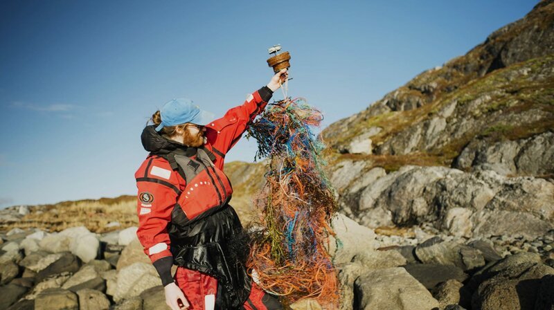 Filmemacher Steffen Krones auf den Lofoten mit einer GPS-Boje, die sich auf ihrer Reise in Plastiknetzen verfangen hat. – Bild: MDR/​ravir film