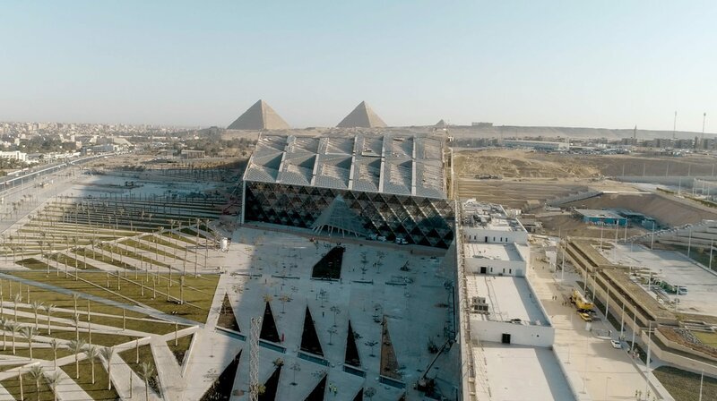 Blick von oben auf das Grand Egyptian Museum mit den Pyramiden im Hintergrund. – Bild: BR