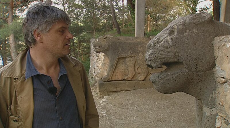 Raoul Schrott vor einem antiken, steinernen Löwen in Karatepe. – Bild: BR