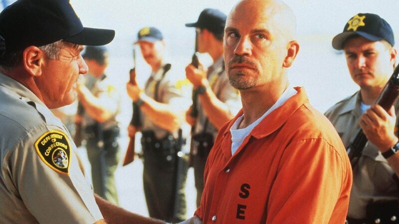 Cyrus Grissom (John Malkovich, r.), einer der gefährlichsten Schwerverbrecher und ein schlauer Kopf, hat einen Plan entworfen, wie er mit dem Gefangenenflieger „Con Air“ flüchten kann. Die Verwendung des sendungsbezogenen Materials ist nur mit dem Hinweis und Verlinkung auf RTL+ gestattet. – Bild: RTL /​ Touchstone Pictures Die Verwendung des Materials von RTL Deutschland ist nur zur redaktionellen Berichterstattung im Zusammenhang mit der Sendung unter Angabe der Credits/​Quellenangabe und Beach