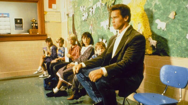 Kimble (Arnold Schwarzenegger, r.) muss sich in seiner Undercover-Rolle als Kindergartenlehrer umstellen – nicht nur auf niedrige Sitze, sondern auch den „Terror“ der „lieben Kleinen“. – Bild: ZDF und Phillip V. Caruso./​Phillip V. Caruso