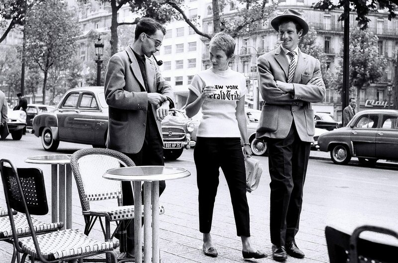 Während der Dreharbeiten in Paris zum Film „Außer Atem“ für die berühmte Szene, in der Jean-Paul Belmondo (re.) und Jean Seberg (Mi.) auf der Champs Elysées spazieren gehen – Bild: Jacques Boissay/​akg-images