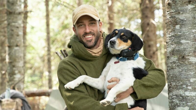Survivalist Jason is all smiles as he holds his mixed-breed dog Maggie near their campsite. (National Geographic) – Bild: National Geographic /​ National Geographic
