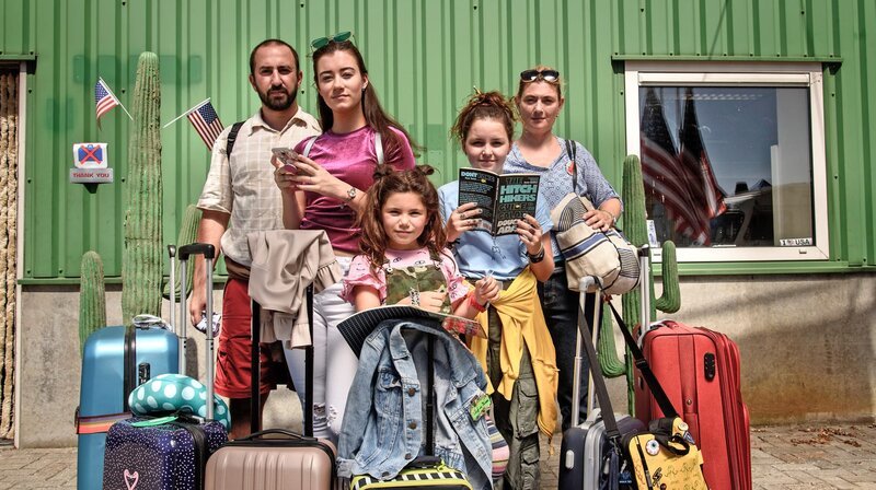 Jip (Layla Zara Seme, Mi.) und ihre Familie ist in Amerika angekommen und wartet auf ihren Miet-Camper. – Bild: NDR/​Pief Weyman