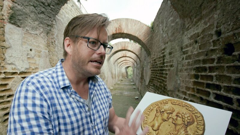 Archäologieprofessor Kevin Dicus mit einer Münze aus dem ersten Monat von Neros Regierungszeit, die den Kaiser mit seiner Mutter Agrippina zeigt. – Bild: arte Archäologieprofessor Kevin Dicus mit einer Münze aus dem ersten Monat von Neros Regierungszeit, die den Kaiser mit seiner Mutter Agrippina zeigt. – Bild: arte